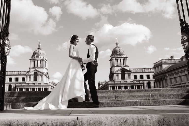 Bride and groom by the River Thames on the steps of the Royal Naval College in Greenwich.